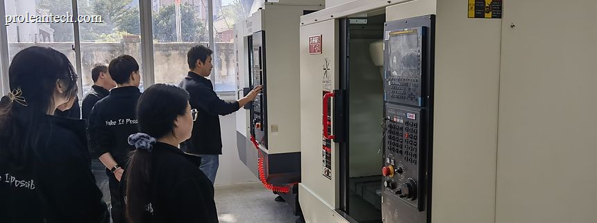 People gathered at the control panel of a CNC machining centre on the shop floor