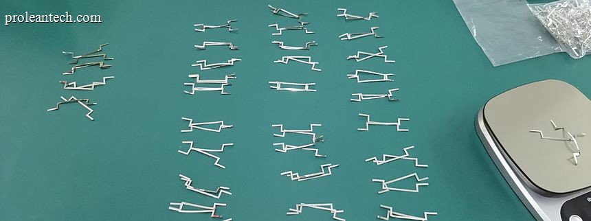 Rows of small machined parts laid out on a green inspection mat for counting