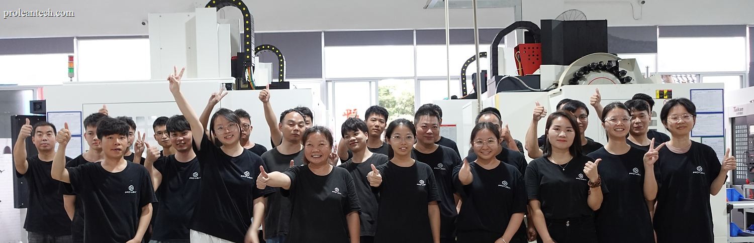 The Proleantech team of about twenty-five people, in workwear, standing in a row between the machining centres in the Shenzhen workshop