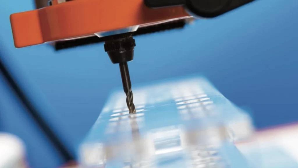 An image showing a CNC drilling shaping holes in acrylic material with precision.