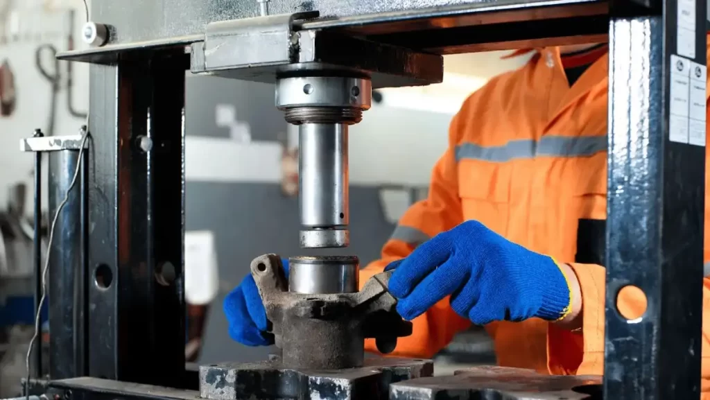 Worker using a hydraulic press in manufacturing.