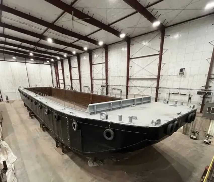 Coated steel barge hull under construction indoors  