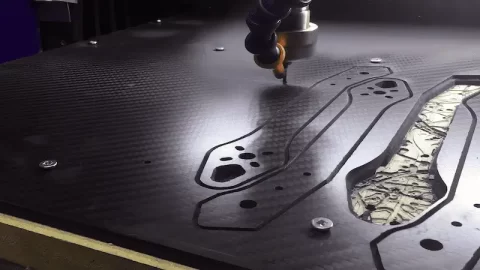Laser cutting shapes in a carbon fiber sheet.