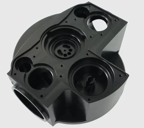 Black Delrin (acetal/POM) CNC-machined manifold housing with multiple precision-drilled ports and bores.