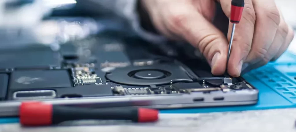 Technician repairing laptop with precision screwdriver and threaded fasteners