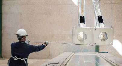 Operator guiding a galvanized steel plate out of the zinc bath with a hooked pole