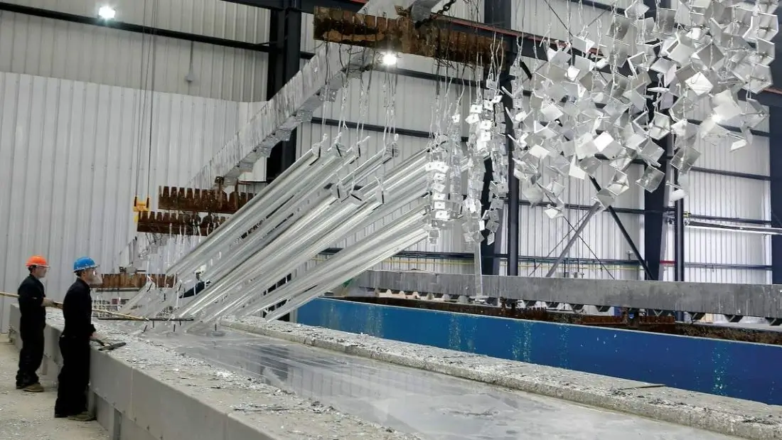 Overhead crane lifting a jig of steel fabrications out of the molten zinc bath on a galvanizing line