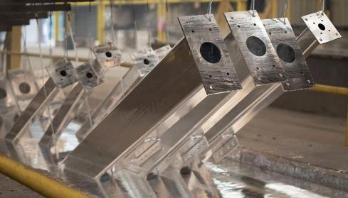 Large steel fabrications on a jig being lifted from the hot-dip zinc bath