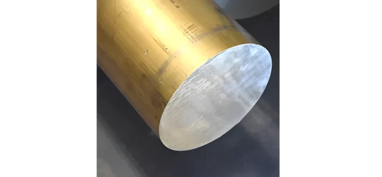A sawn brass round bar &mdash; polished end face, oxidised golden surface, machining marks visible