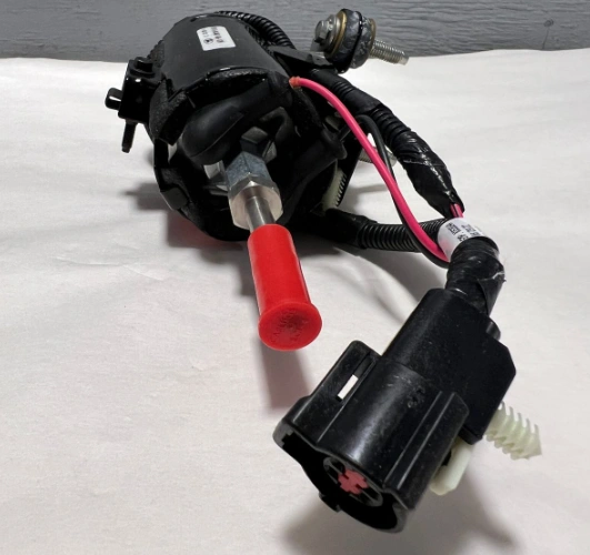 An image of a car fuel pump showing a black and red component connected with wires to a black component on a white surface