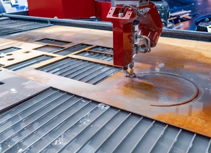 CNC waterjet cutting machine slicing through a metal plate with a high-pressure water stream