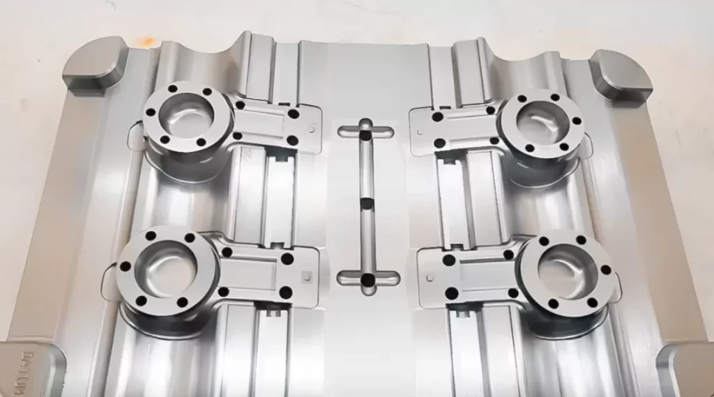 Top-down view of a precision-machined aluminum injection mold with four cavities and a central runner system.  