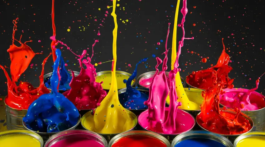 Splashing paint in red, blue, yellow, and pink out of open containers with a dark background