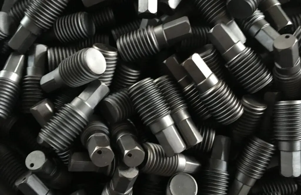 Randomly arranged titanium fasteners with a black anodized finish.