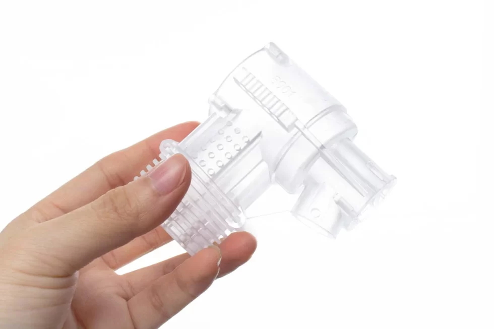 Close-up of a female hand holding a gun-shaped clear SLA printing shape