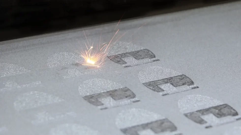 The image depicts the Direct Metal Laser Sintering (DMLS) process, where a high-powered laser selectively fuses metal powder layer by layer to create a solid component.