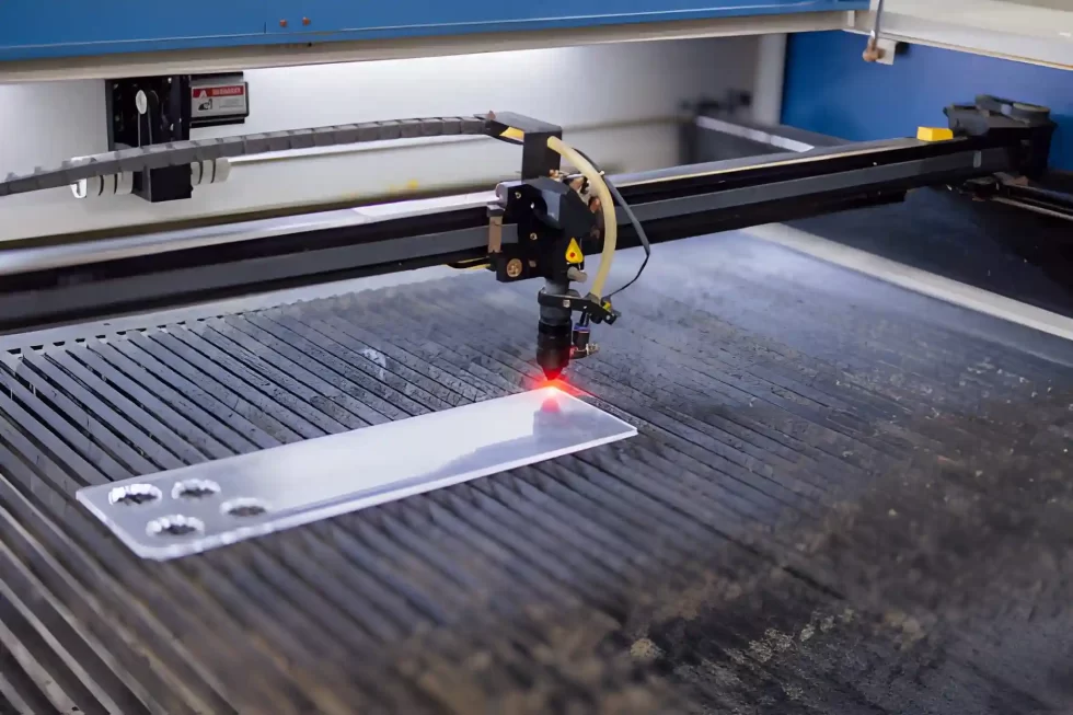 Closeup industrial CO2 laser cutting machine working with high powered red laser beam on acrylic.