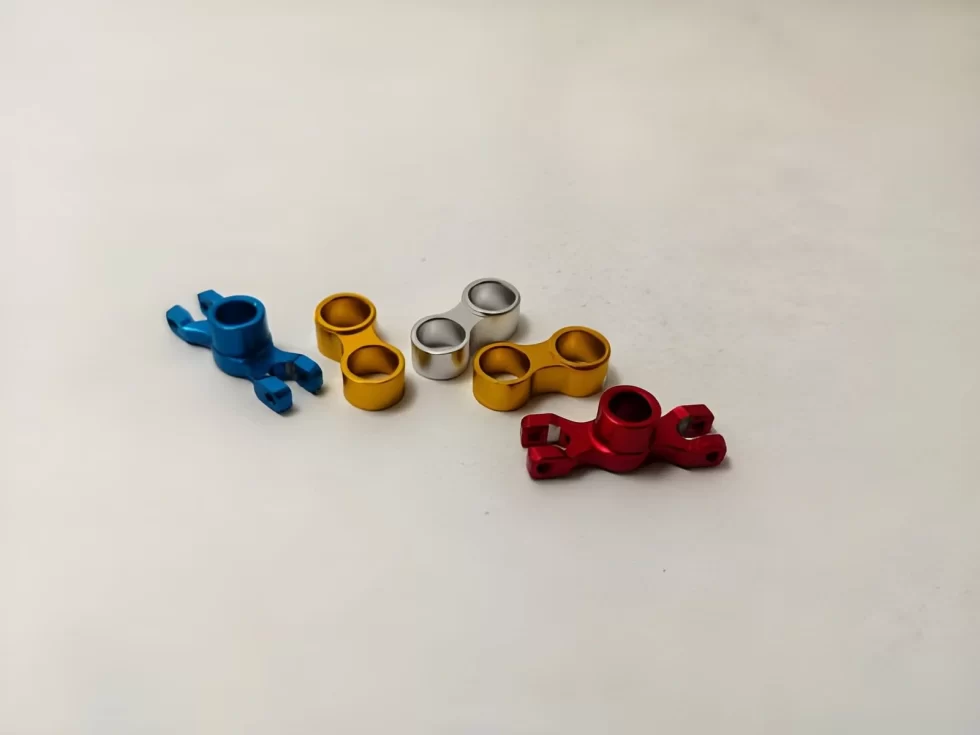 The image shows CNC-machined, anodized aluminum parts with a smooth, finished, vibrant-colored surface. 