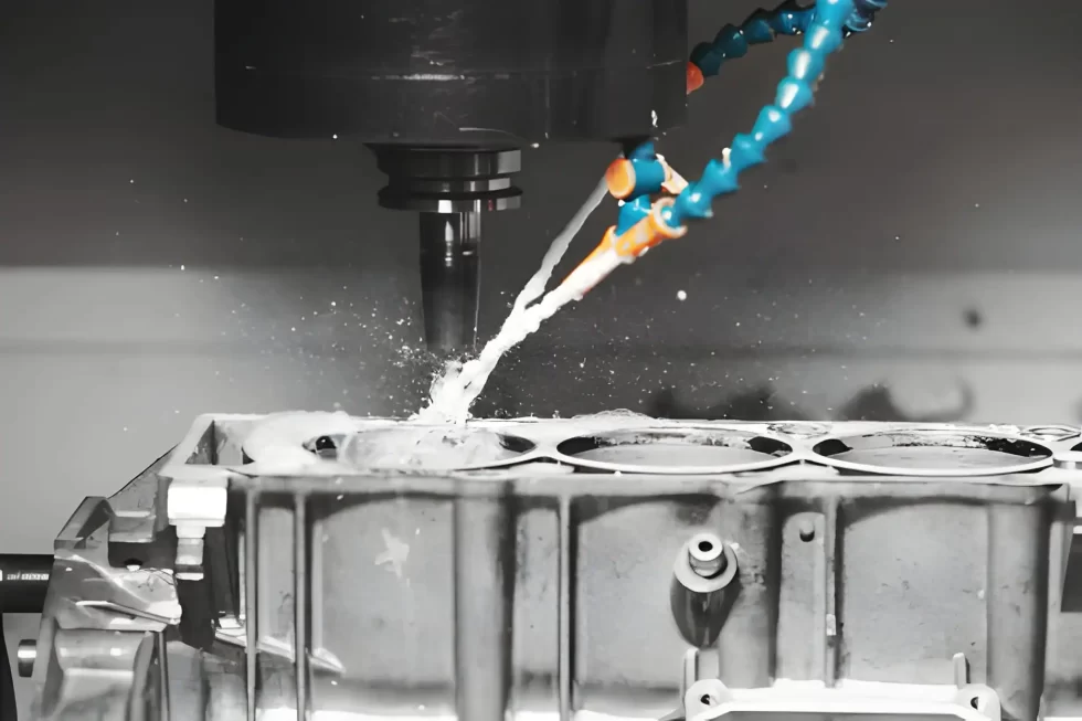 CNC milling machine machining an automotive engine component with a constant coolant supply.