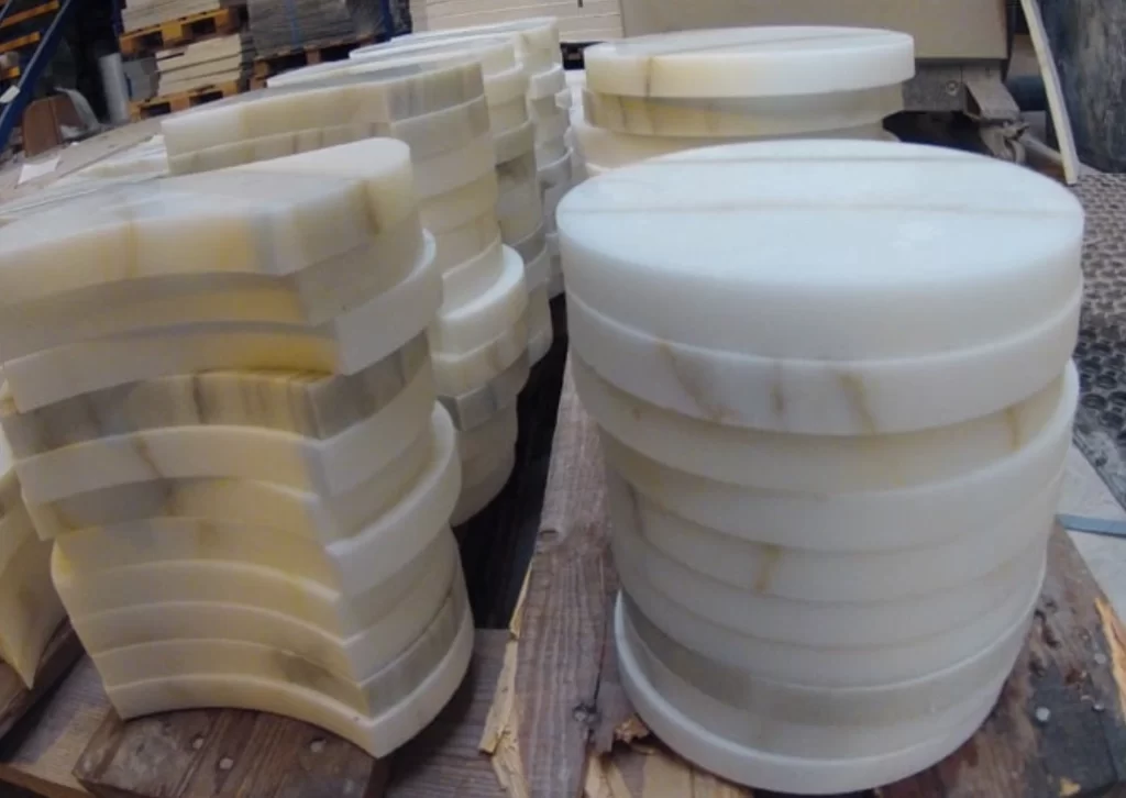 White ceramic cylindrical parts with spiral grooves and smooth surfaces cut by abrasive waterjet on workshop table