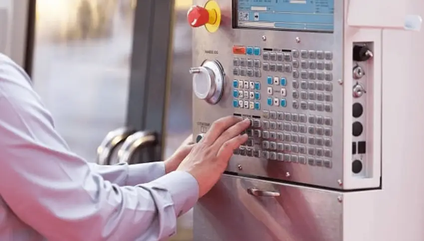 Operator hands programming the CNC machine control panel