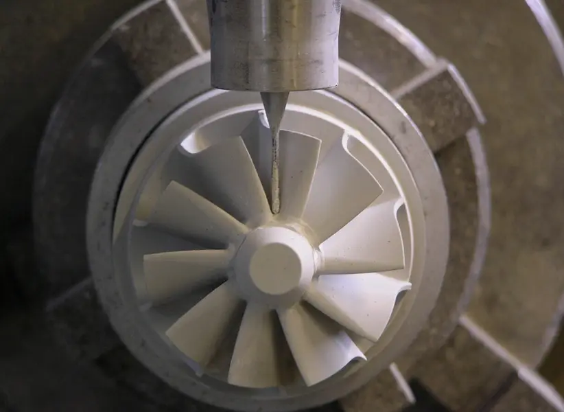 CNC tool machining green-state ceramic turbine impeller with curved blades before final sintering