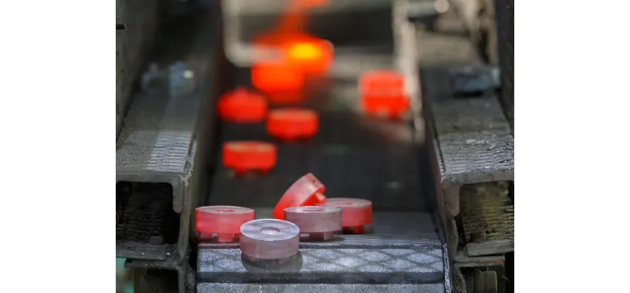 Red hot steel gears on a conveyor belt with cooled gears in front