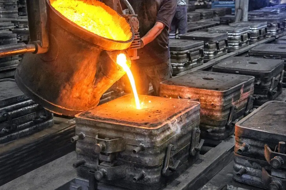 Close view of an operator pouring liquid metal in mold for casting.
