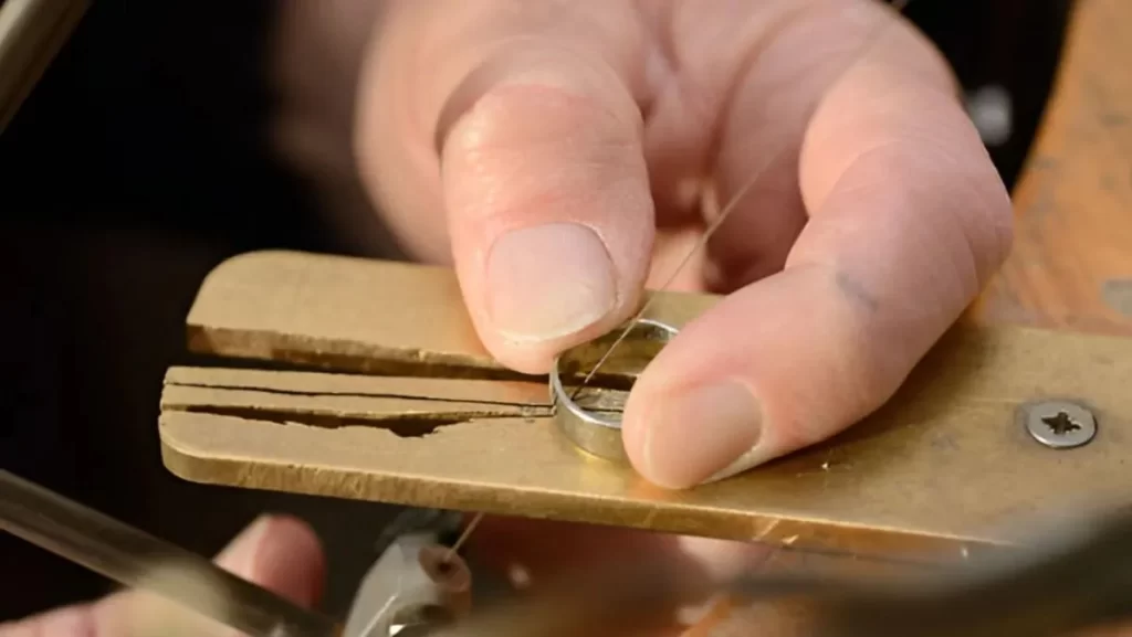 A close-up of a person's hands holding a small, round metal piece