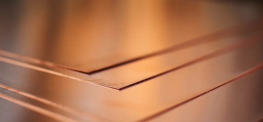 Close-up of multiple polished copper metal sheets neatly stacked with reflective surfaces.