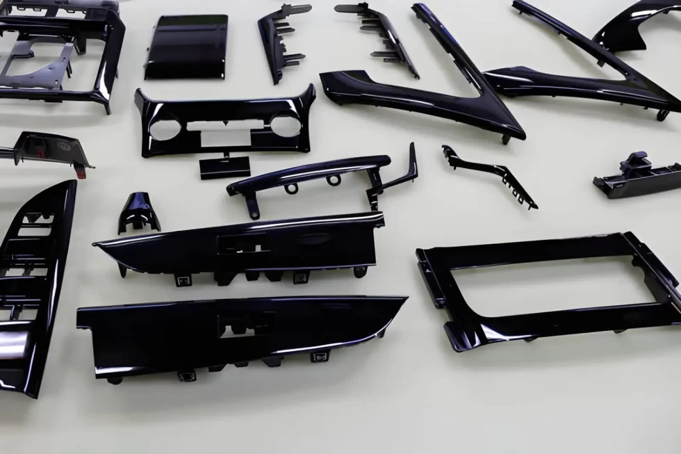 Glossy black automotive interior trim pieces placed on a workshop table.