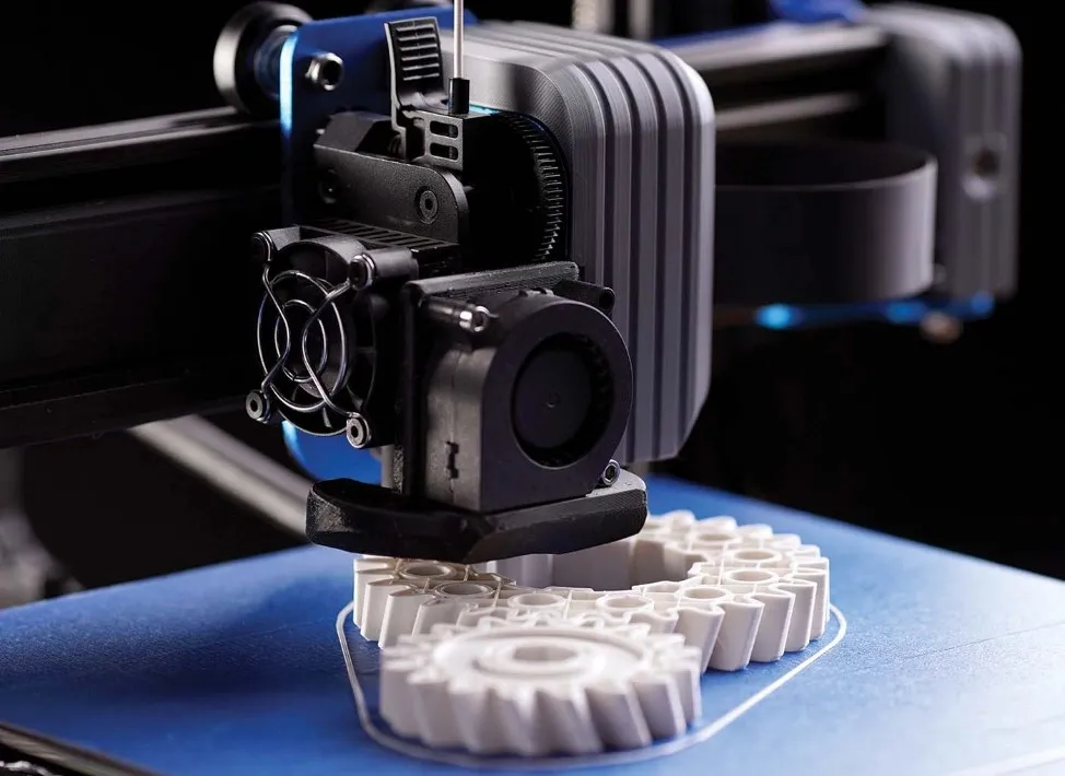 A close-up image of a compact FDM 3D printer on a blue platform