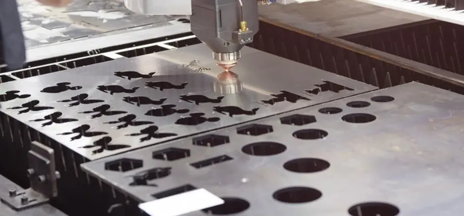 Fiber laser head precisely cutting intricate decorative shapes and geometric patterns through stainless steel sheet during laser cutting materials process.