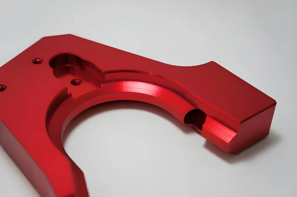 The image shows a red-colored anodized aluminum part with a uniform surface finish. 