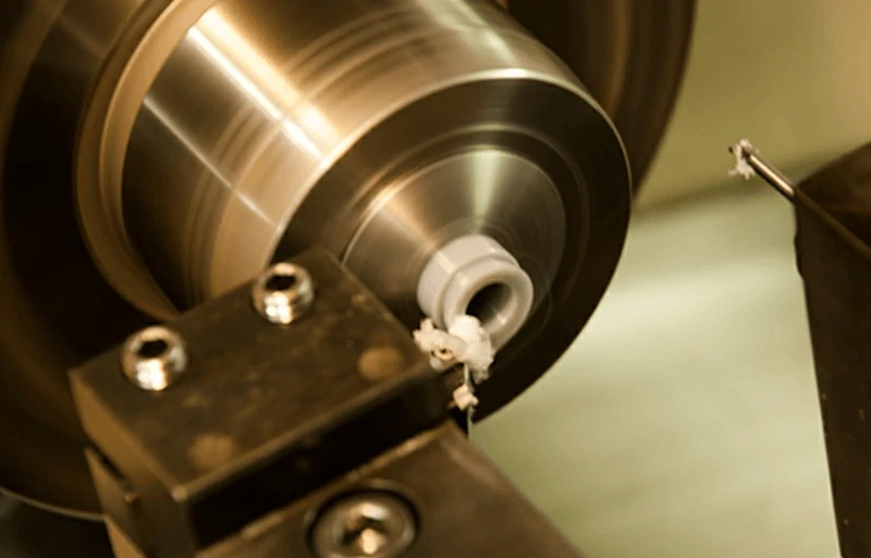 CNC lathe turning polypropylene workpiece with cutting tool producing machined concentric grooves